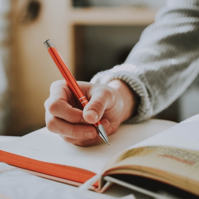 Hand holding a pen, primed to write in a book